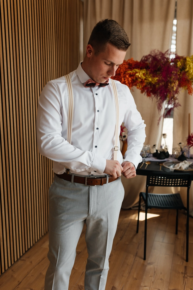 Bräutigam Fabian richtet seine Hosenträger und die Fliege – ein cooles, maskulines Portrait.