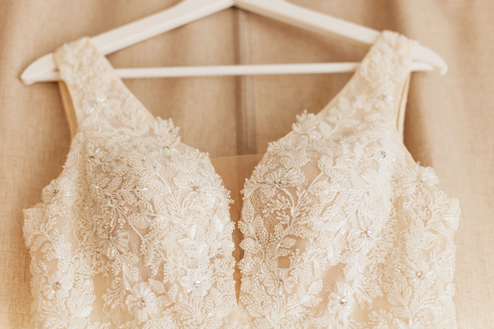 Close-Up der feinen Spitze und Knopfleiste des Brautkleides, bevor die Braut hineinschlüpft.