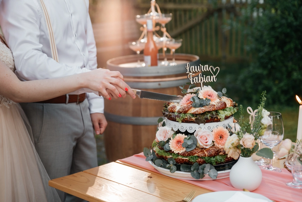 Das Brautpaar schneidet eine herzhafte bayerische Brezeltorte an – die perfekte Alternative zu Süßem.