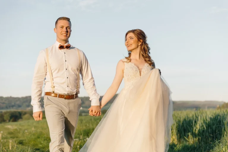 Brautpaar Laura und Fabian spazieren entspannt und lachend über ein Feld im Abendlicht bei Neumarkt.