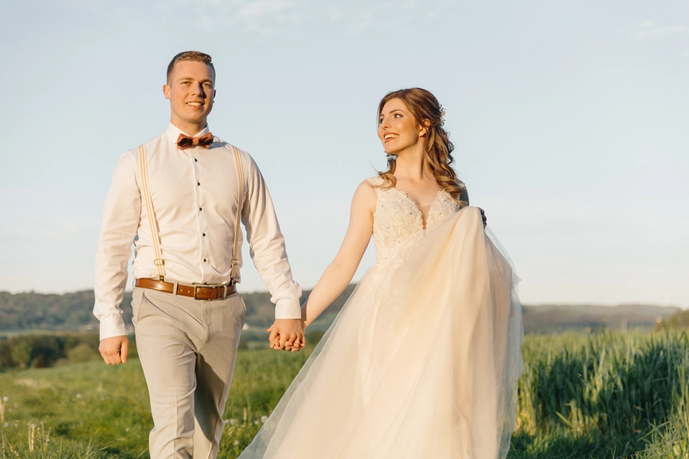 Brautpaar Laura und Fabian spazieren entspannt und lachend über ein Feld im Abendlicht bei Neumarkt.