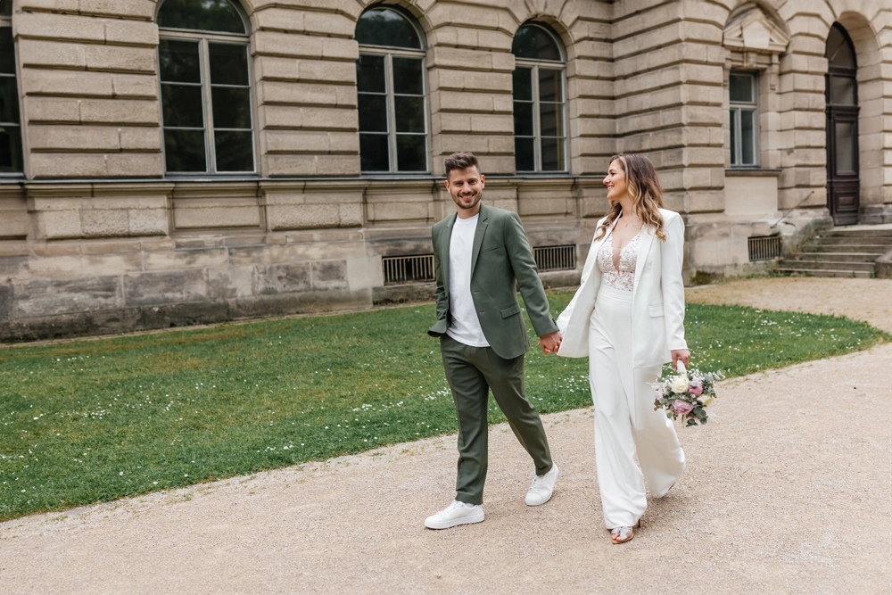 Brautpaar spaziert vor der historischen Architektur der Orangerie in Erlangen.