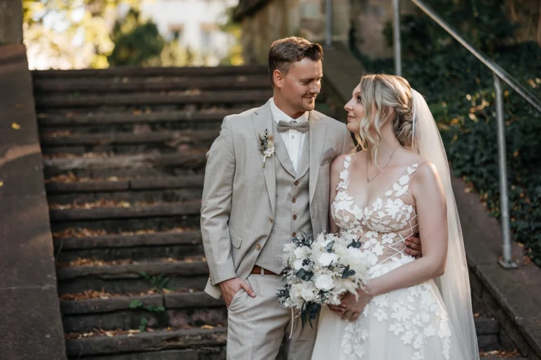 Brautpaar bei der freien Trauung im Stadtpark Fürth steht auf einer Steintreppe und schaut sich verliebt an.