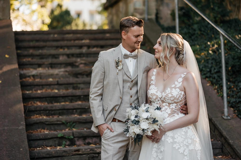 Brautpaar bei der freien Trauung im Stadtpark Fürth steht auf einer Steintreppe und schaut sich verliebt an.