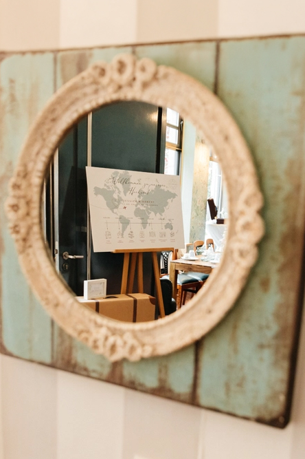 Weltkarte auf einer Staffelei spiegelt sich in einem runden Wandspiegel