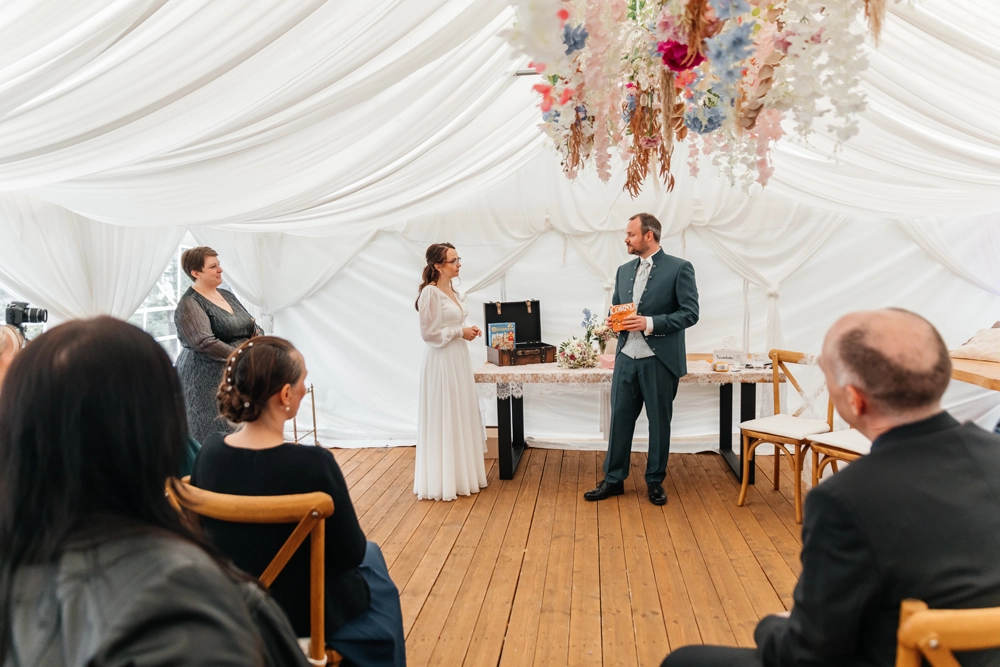 Brautpaar beim Koffer-Ritual vor den sitzenden Hochzeitsgästen