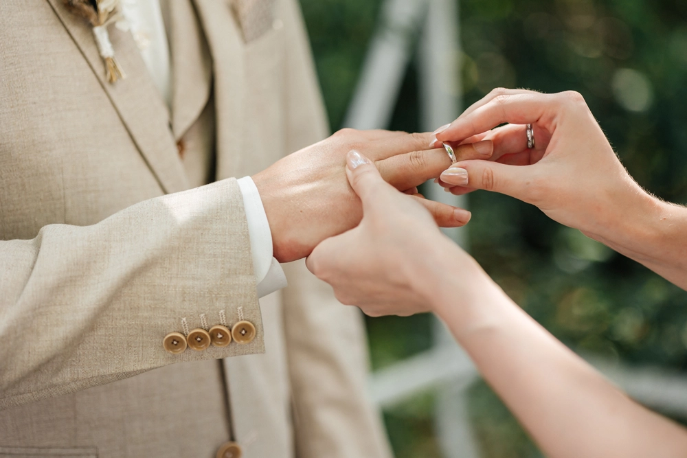 Detailaufnahme des Ringwechsels: Bräutigam steckt der Braut den Ehering an.