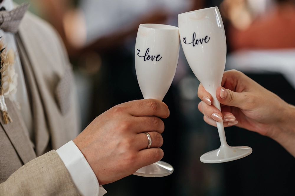 Das Brautpaar stößt mit Sektgläsern mit der Aufschrift Mr. und Mrs. auf die Hochzeit an.