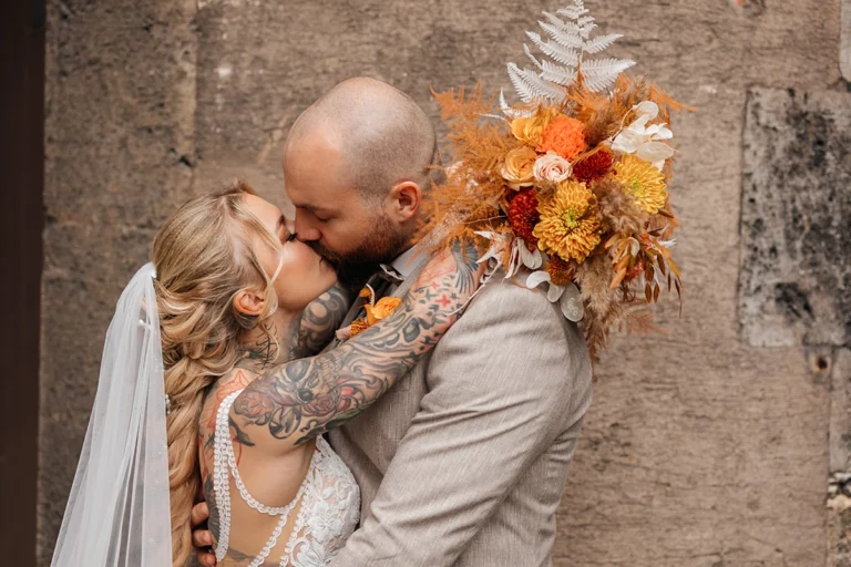 Brautpaar bei ihrer Hochzeit im Schloss Faber-Castell, intimes Portrait, Bräutigam hält Wange der Braut, Handtattoos sichtbar.