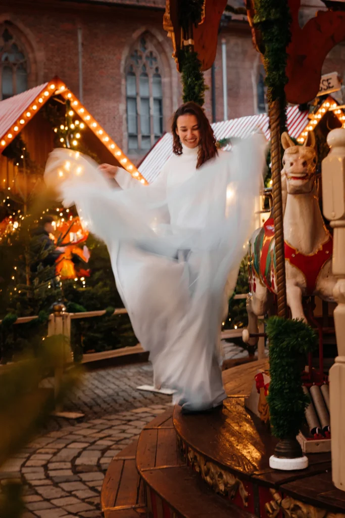Romantisches Winterportrait einer Frau vor dem weihnachtlich beleuchteten Karussell auf dem Nürnberger Christkindlesmarkt.