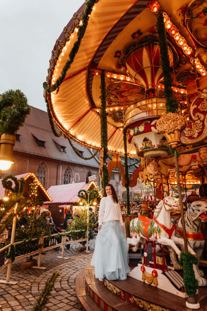 Stimmungsvolle Portraitaufnahme einer Frau mit weihnachtlicher Dekoration am Karussell des Nürnberger Christkindlesmarkts.
