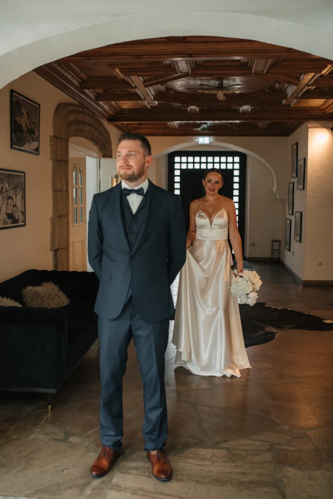 Hochzeitspaar posiert in historischem Saal mit Holzdecke – klassisch und elegant.