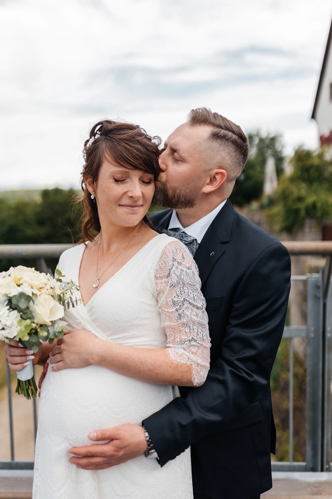 Bräutigam küsst Braut auf Stirn (Inniges Portrait)