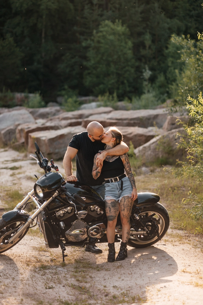 Paar lehnt entspannt am Motorrad, lockeres Posing für Männer, die Fotos eigentlich hassen.