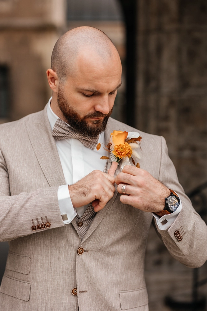 Bräutigam richtet sein Jackett, cooler Look mit beigem Anzug und Fliege.