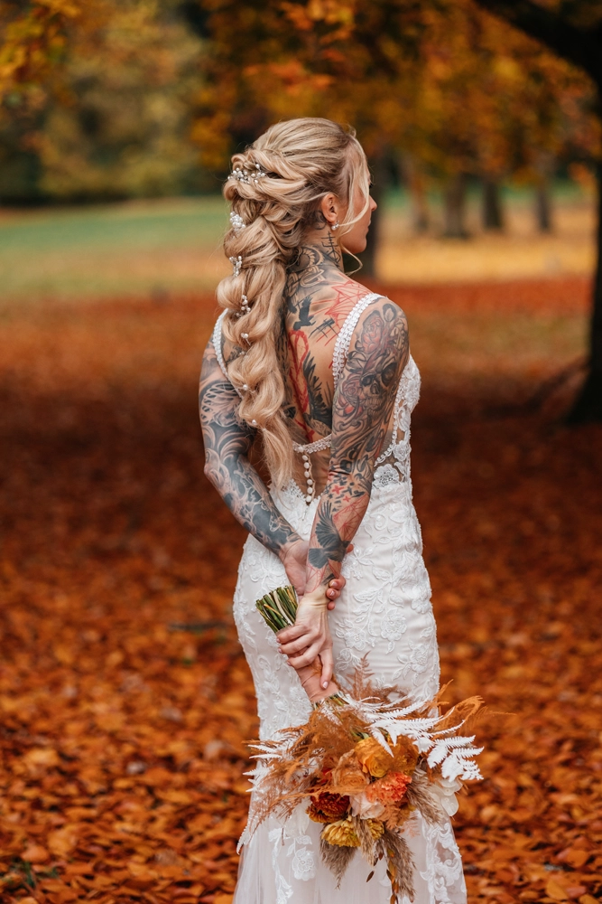 Rückenansicht der Braut im Spitzenkleid, großes Rückentattoo sichtbar