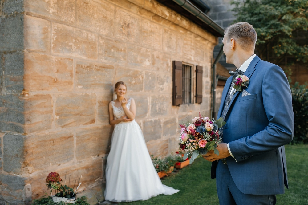 Entspanntes Portrait: Brautpaar lehnt lässig an der Außenseite der Kirche St. Michael.