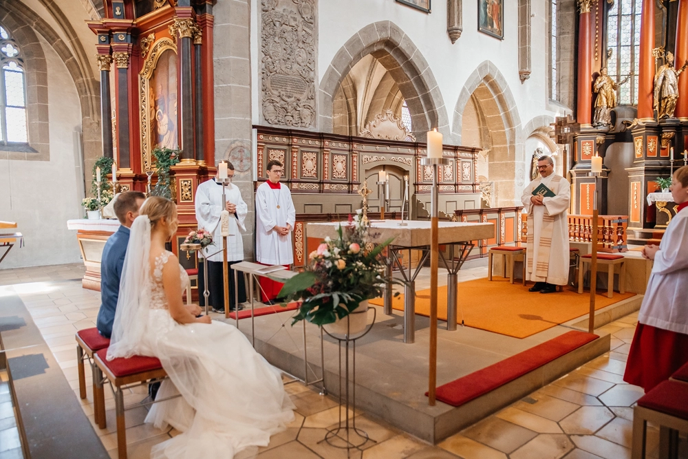 Seitliche Aufnahme des Brautpaares am Altar, emotionaler Moment.