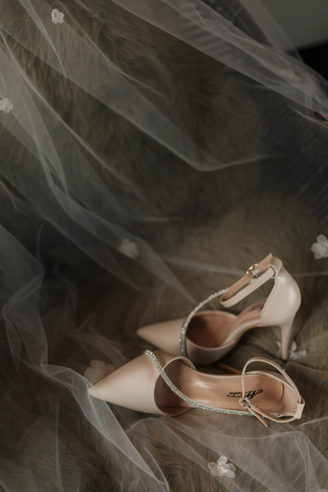 Detailaufnahme des Brautschleiers und der Schuhe, weiches Licht und Tüll.