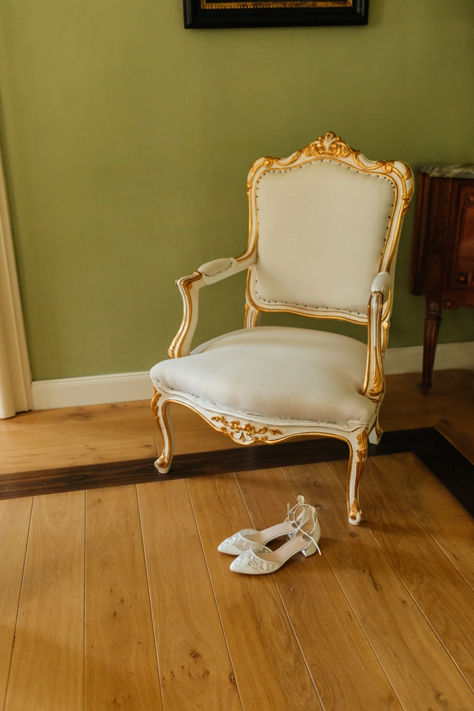 Detailaufnahme der weißen Brautschuhe auf Holzboden