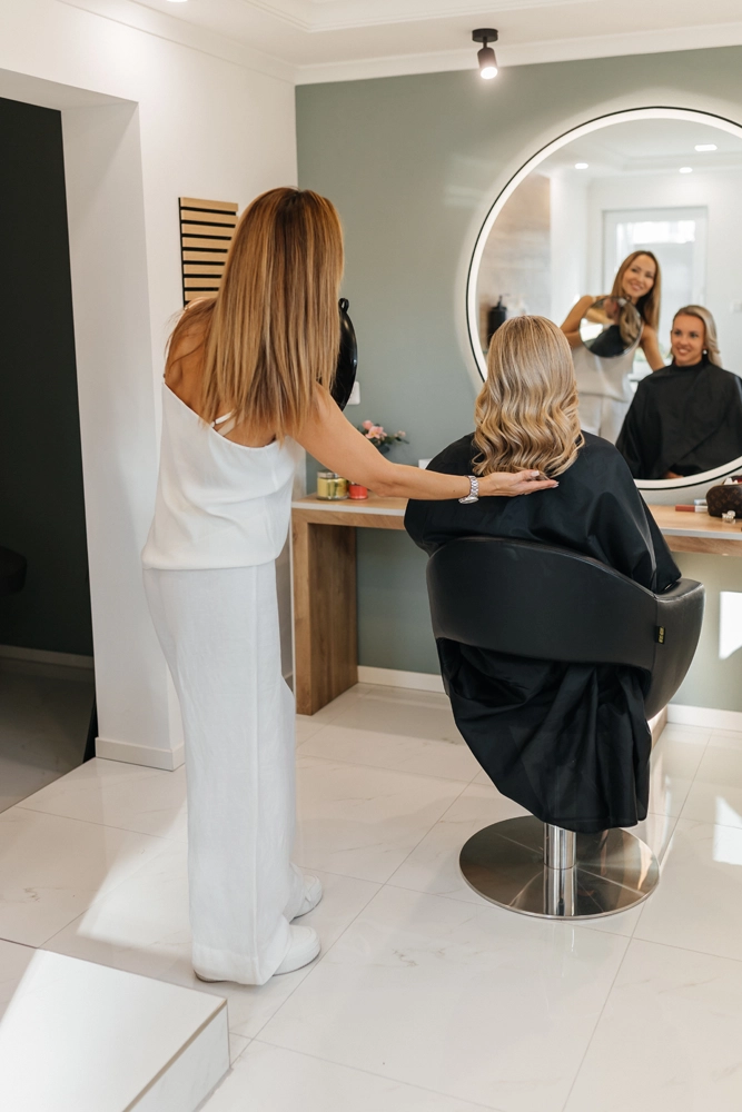 Nadja Laber betrachtet zufrieden das fertige Haarstyling im Spiegel – ein Moment der Ruhe im Salon.