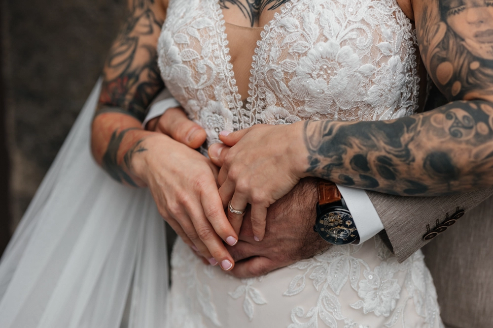 Nahaufnahme der Hände des Brautpaares, innige Berührung.