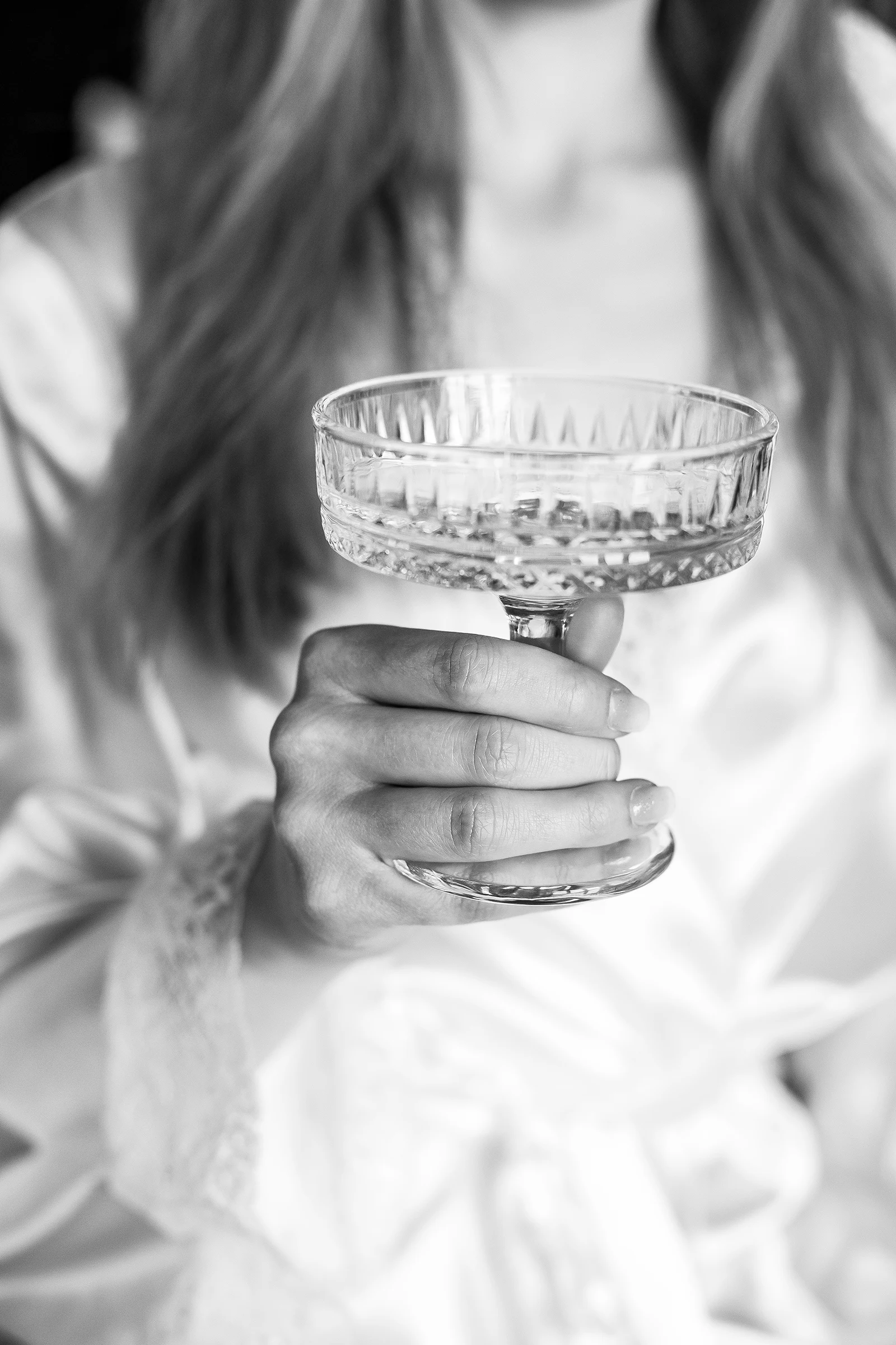 Nahaufnahme der Hände der Braut mit Sektglas, Schwarz-Weiß Fotografie.