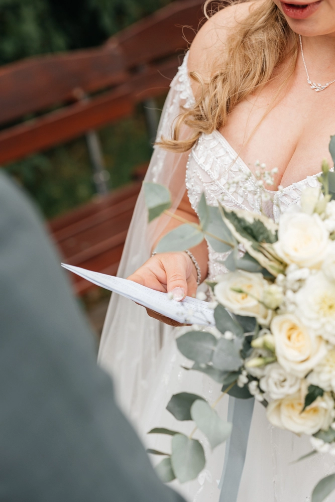 Braut liest Eheversprechen vom Blatt, Detailaufnahme der Hände und des Brautstraußes.