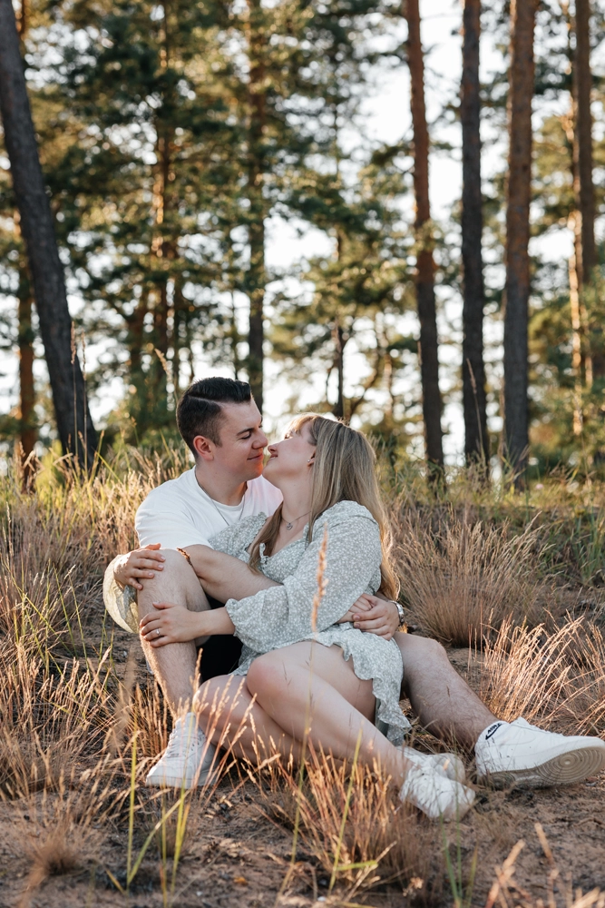 Atmosphärisches Portrait: Paar sitzt entspannt am Waldrand im weichen Abendlicht.