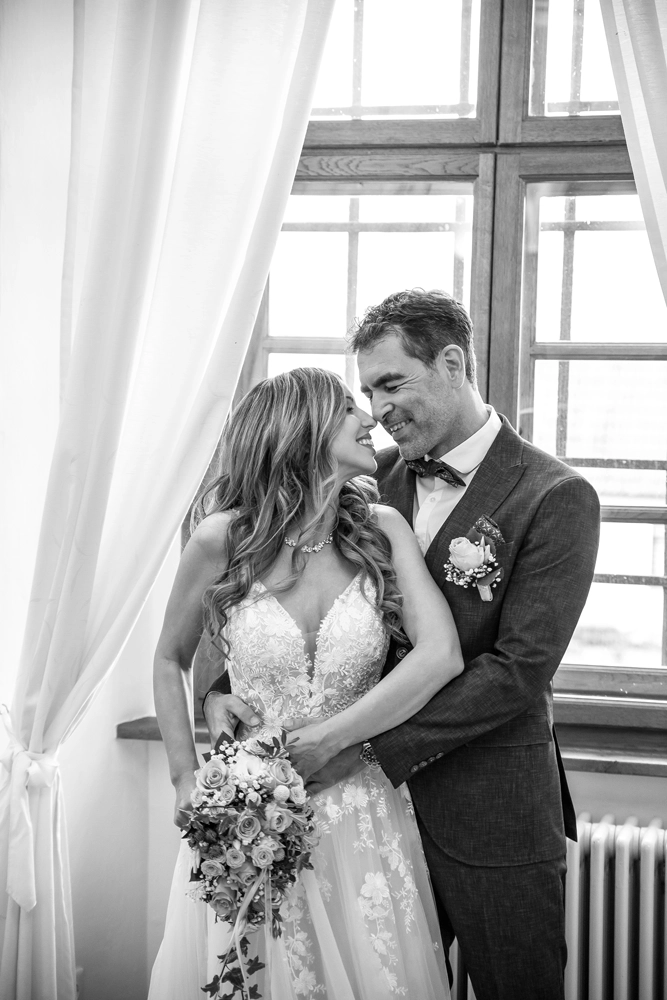 Romantisches Schwarz-Weiß Portrait des Brautpaares im weichen Fensterlicht.