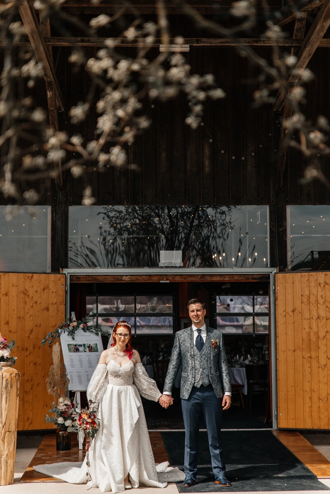 Braut und Bräutigam halten Hände um die Ecke einer Hol scheune vor der Trauung