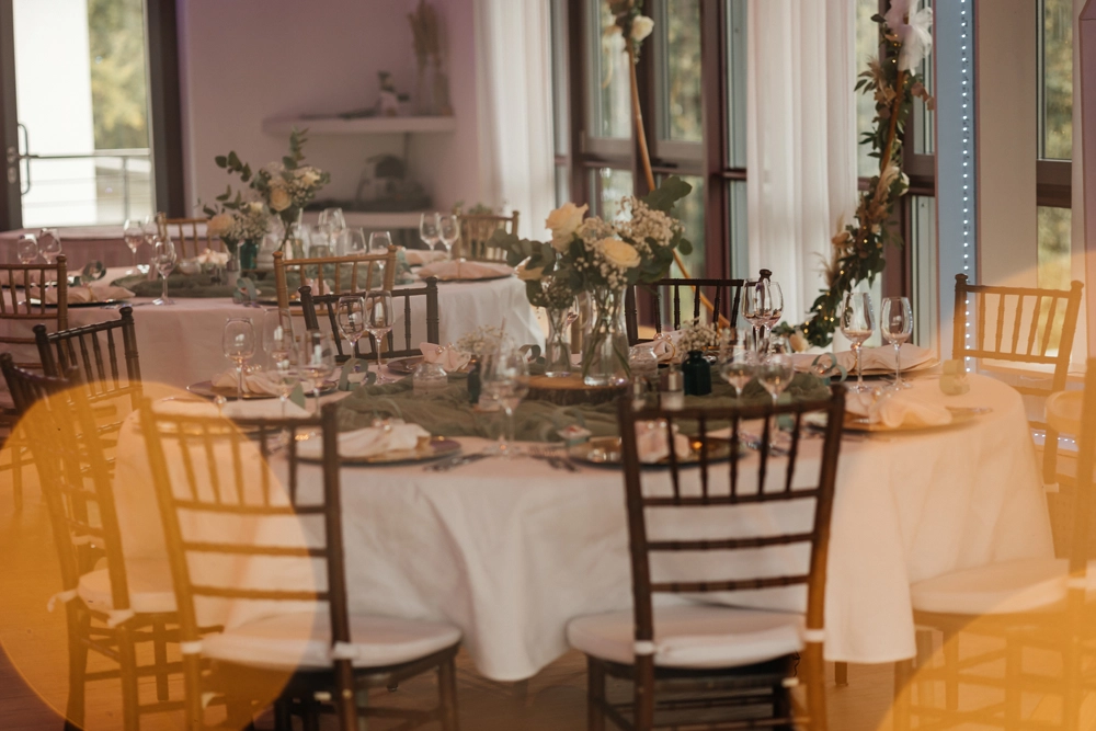 Elegante Tischdeko in Weiß und Gold auf runden Tischen in der FREIRAUM Eventlocation.