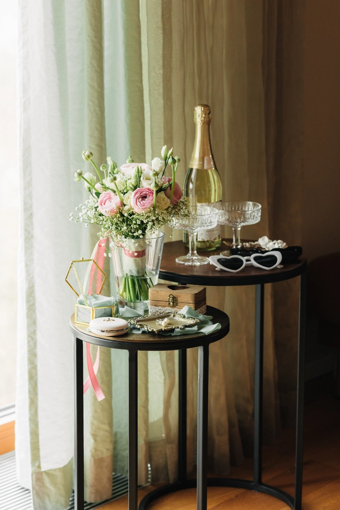 Kleiner Beistelltisch mit Blumen und Sektflasche im Hotelzimmer, stimmungsvolles Licht.