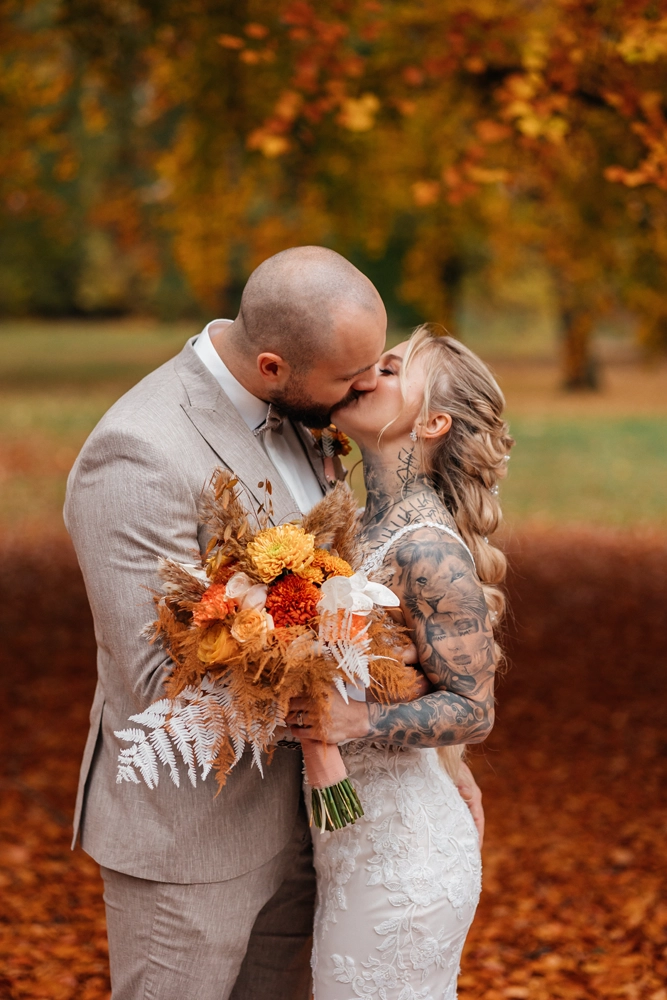 Brautpaar im Herbstlaub, unscharfer oranger Hintergrund, Golden Hour