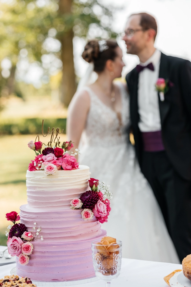 Dreistöckige Hochzeitstorte mit lila Farbverlauf und Blumen