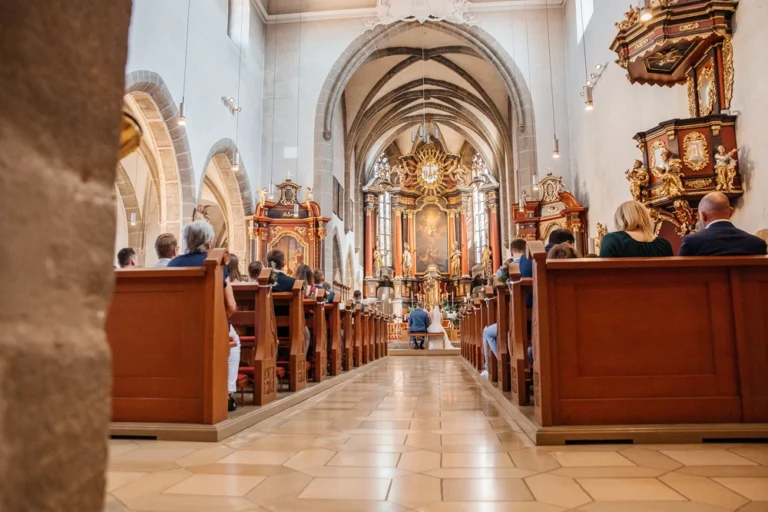 Blick durch das volle Kirchenschiff zum goldenen Altar während der Trauung in St. Michael.