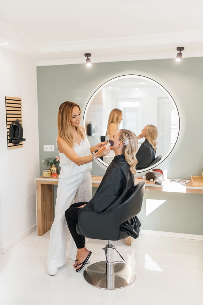 Nadja Laber beim professionellen Auftragen von Make-up mit dem Pinsel im hellen Salon-Ambiente.