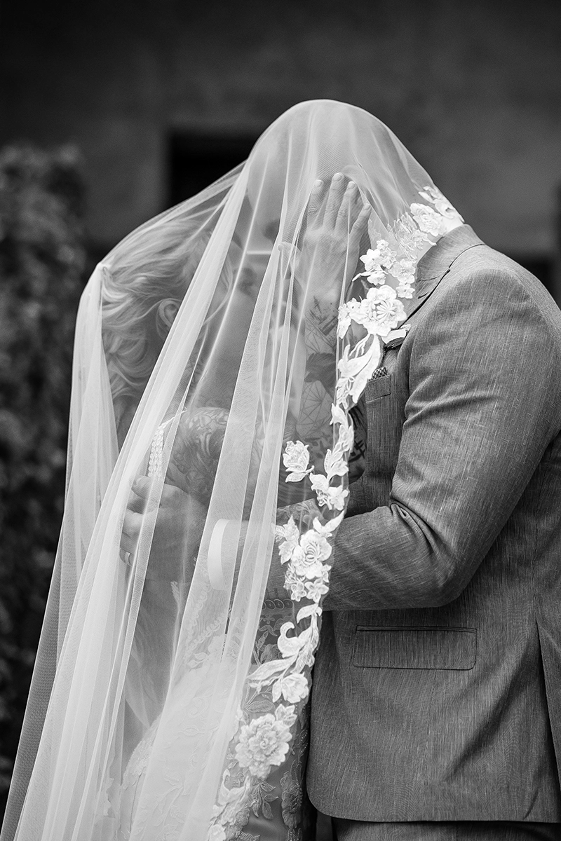 Künstlerisches Schwarz-Weiß Portrait des Brautpaares unter dem Brautschleier