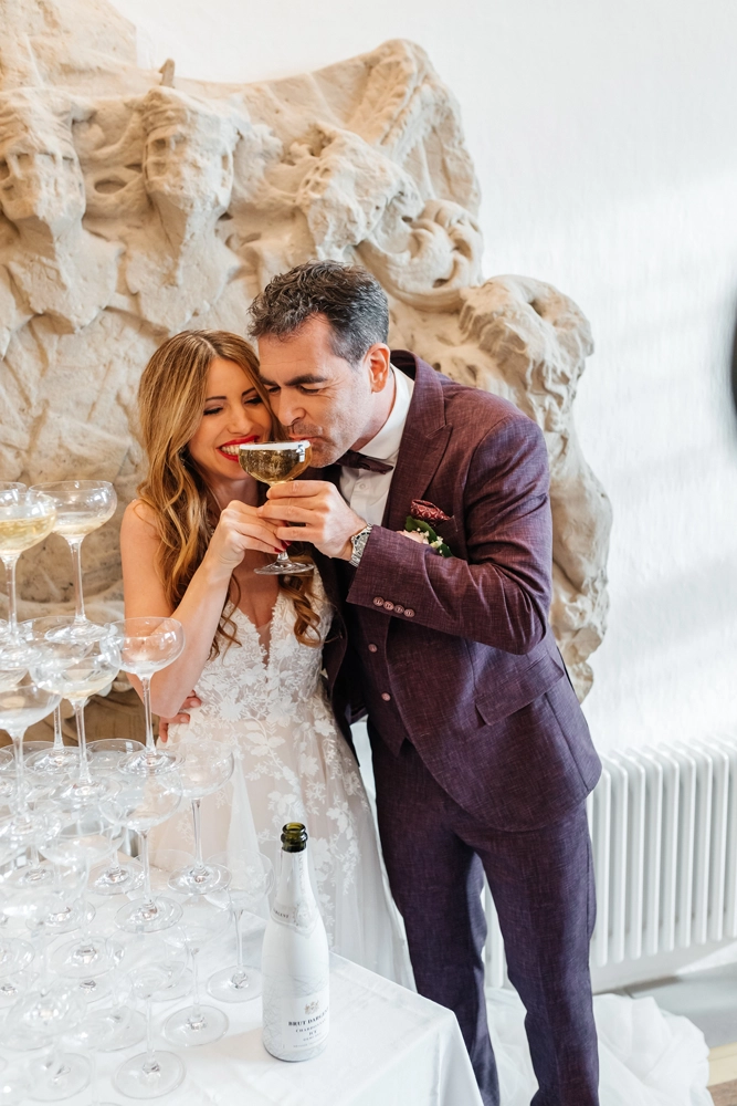 Authentischer Schnappschuss: Braut und Bräutigam trinken Sekt und lachen herzlich.