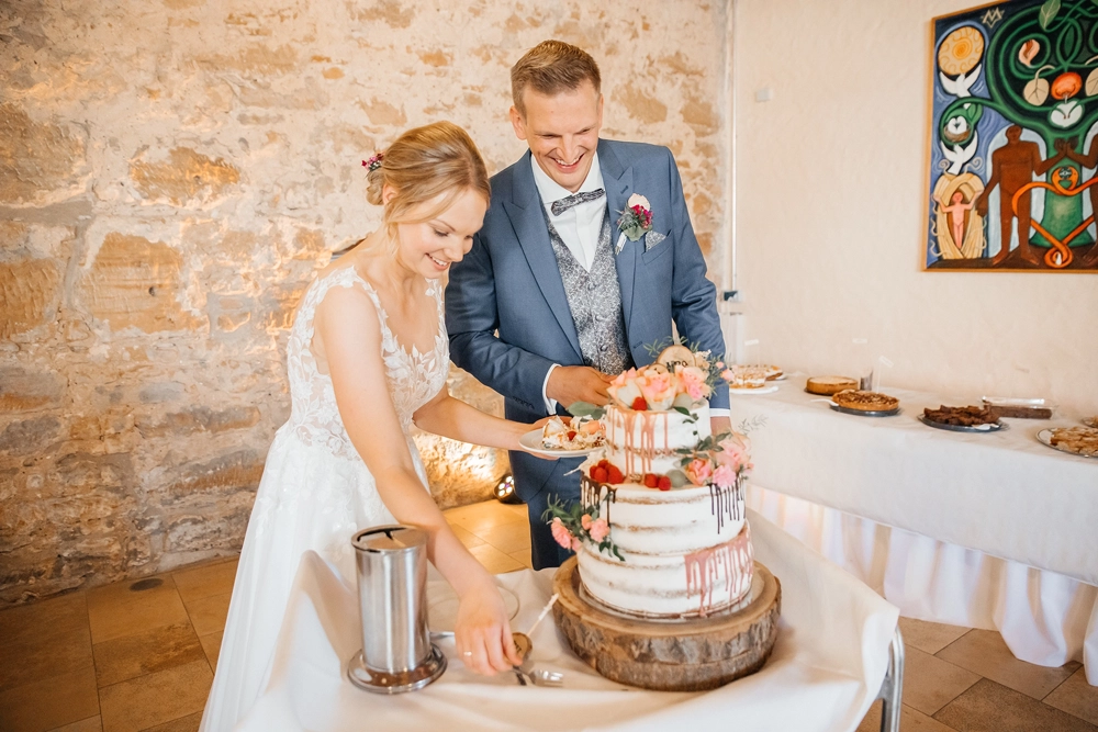 Fröhlicher Tortenanschnitt des Brautpaares in der Scheune