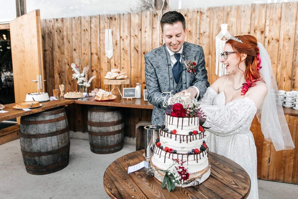 Brautpaar schneidet gemeinsam die Hochzeitstorte an
