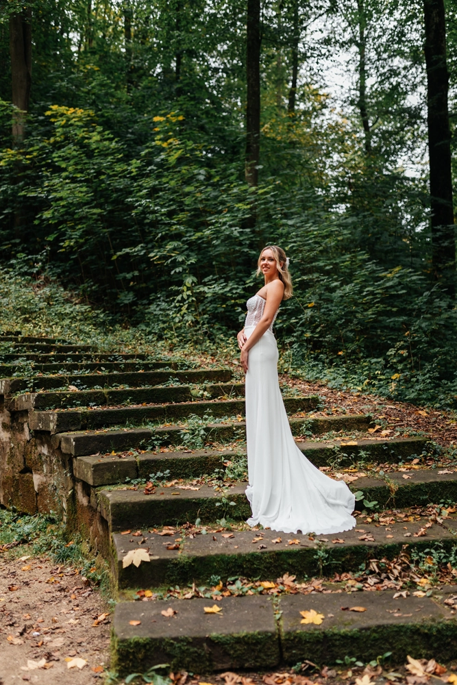 Editorial-Aufnahme einer Braut auf einer historischen Steintreppe inmitten eines herbstlichen Waldes bei Nürnberg.