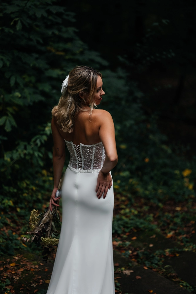 Detailaufnahme der Rückseite des Brautkleides mit Fokus auf die feine Spitze und die fließende Silhouette.