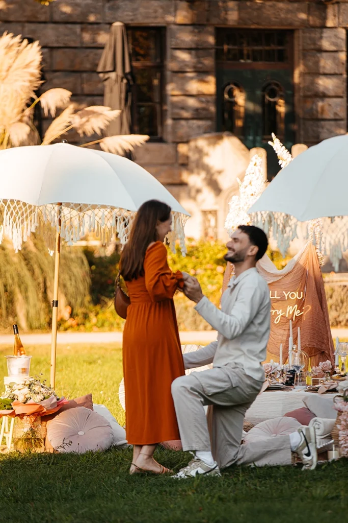 Glückliches Paar umarmt sich nach dem Heiratsantrag beim Boho-Picknick in der Natur.