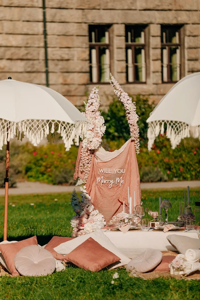 Elegantes Luxus-Picknick Setup im Boho-Stil mit Sonnenschirmen und Kissen für einen Heiratsantrag.