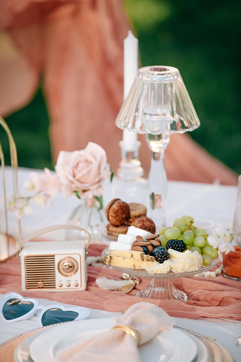 Elegante Tischdekoration mit Retro-Radio und zarten Blumen im Smart Luxury Vibe für ein Verlobungspicknick.