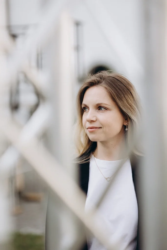 Selbstbewusste Frau im modernen Business-Look lehnt entspannt an einer sonnigen Glasfassade, Personal Branding Shooting in Neumarkt.