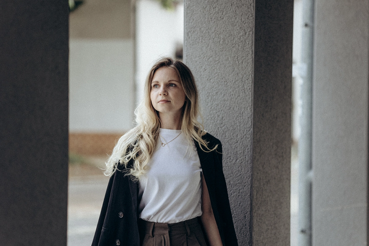 Selbstbewusste Unternehmerin im lässigen Business-Look vor Urbaner-Kulisse in Neumarkt.