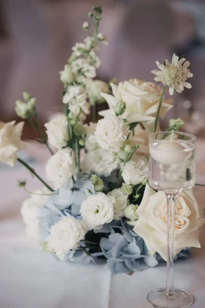 Weiße und hellblaue Blumendekoration mit Kerzen auf der Hochzeitstafel