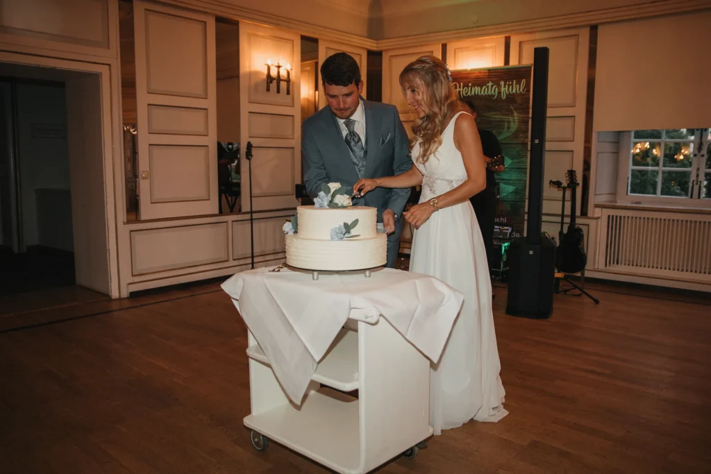 Brautpaar schneidet gemeinsam seine Hochzeitstorte im Schloss-Hotel Neufahrn an